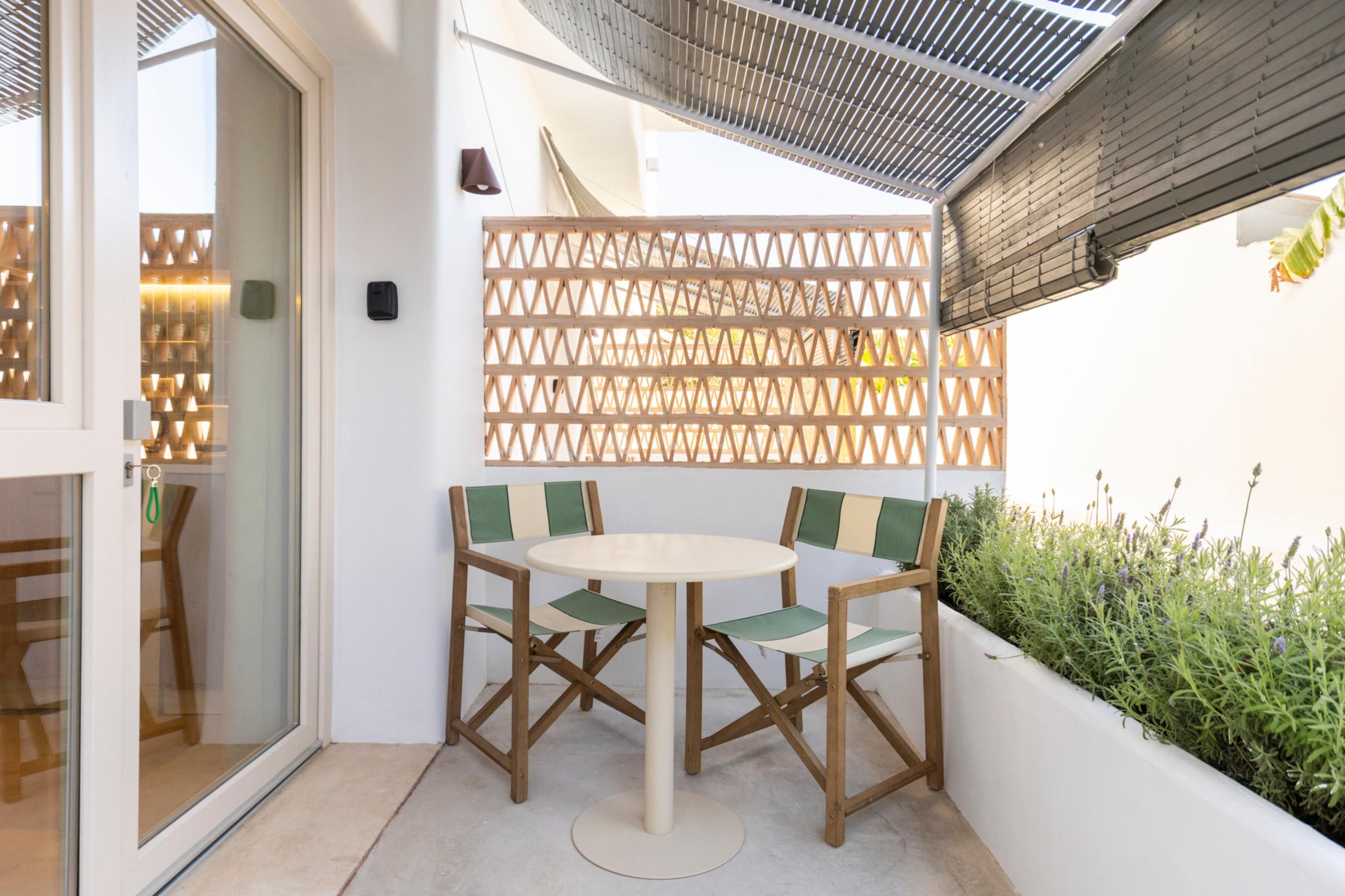 Een terras met een tafel en twee stoelen, een houten schutting en uitzicht op groen.
