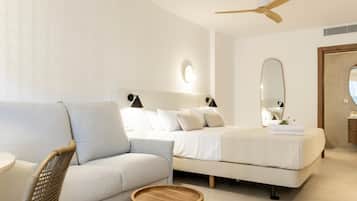 A modern bedroom with a sofa, two beds, a ceiling fan, and a round wooden table.
