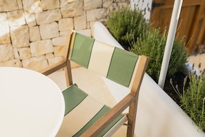 A wooden chair with a green and beige backrest and seat, positioned next to a white table. - Vacança Beach: Ground-floor studio with a terrace (Denia)