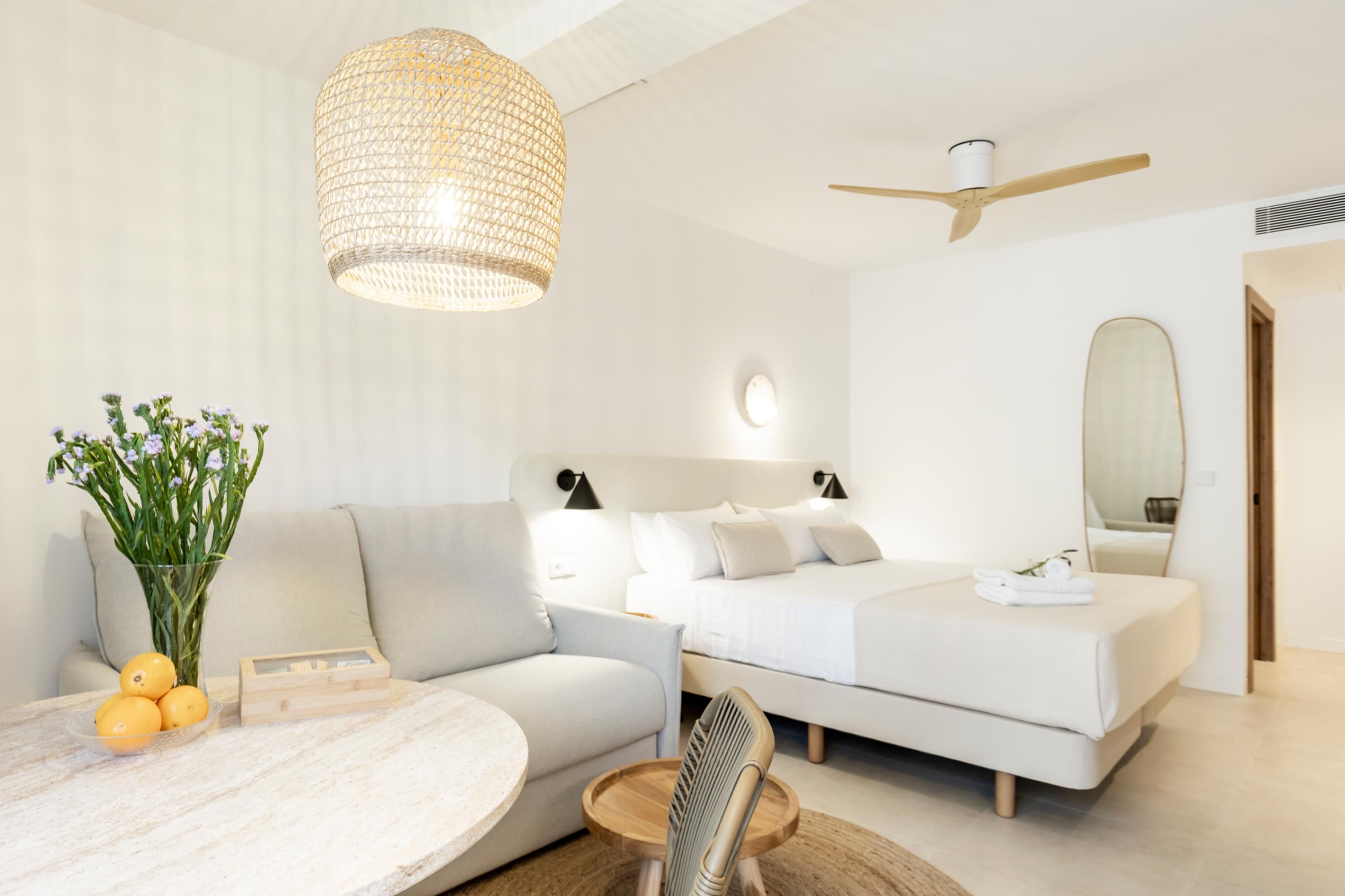 Een moderne slaapkamer met een slaapbank, een bed, een ronde tafel en een plafondventilator.