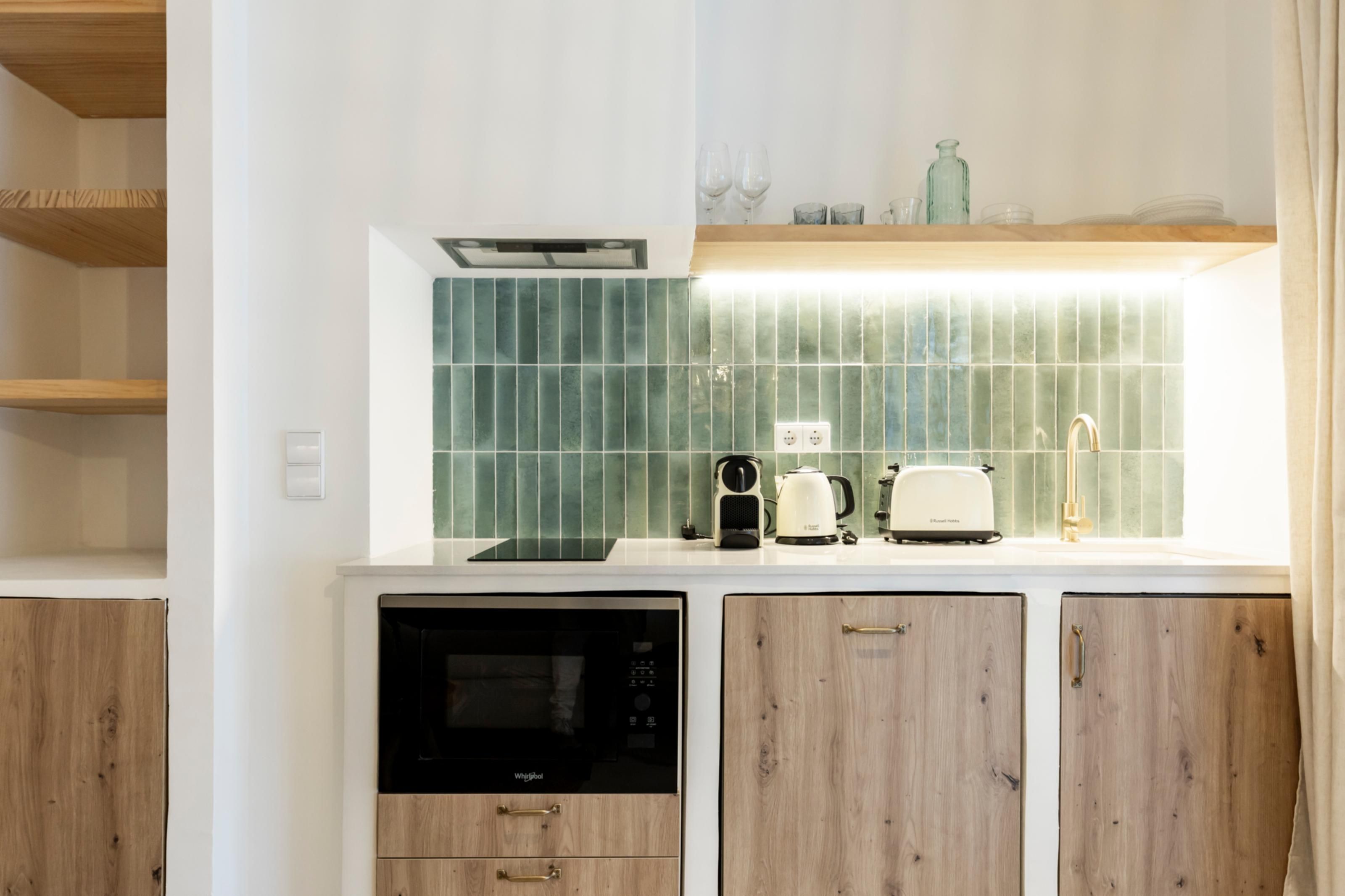 A kitchen with a dishwasher, a toaster, and a kettle on the counter.
