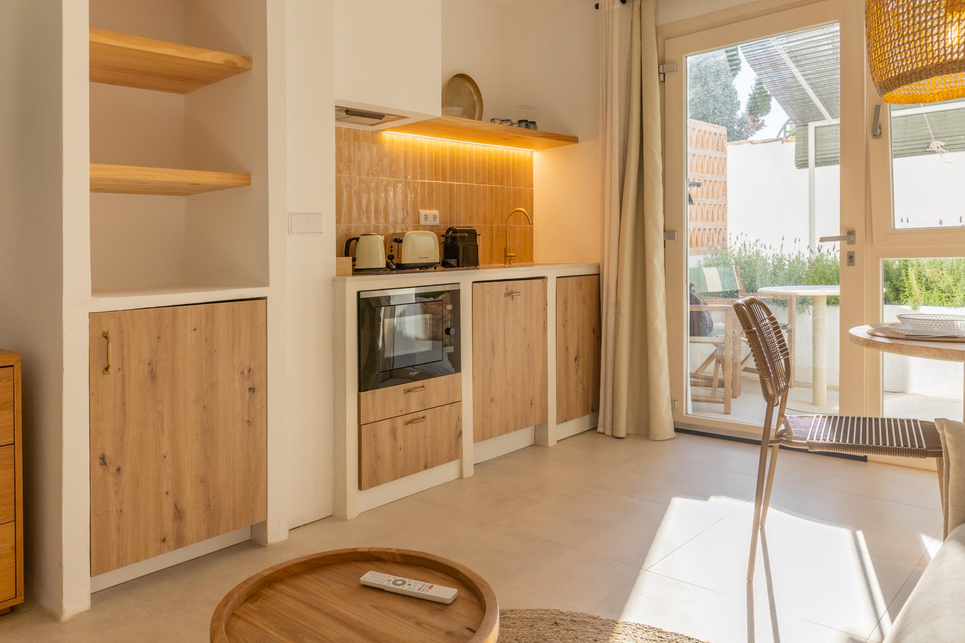 Een moderne keuken met houten kastjes, een inbouwoven en een eethoek met een tafel en stoelen.