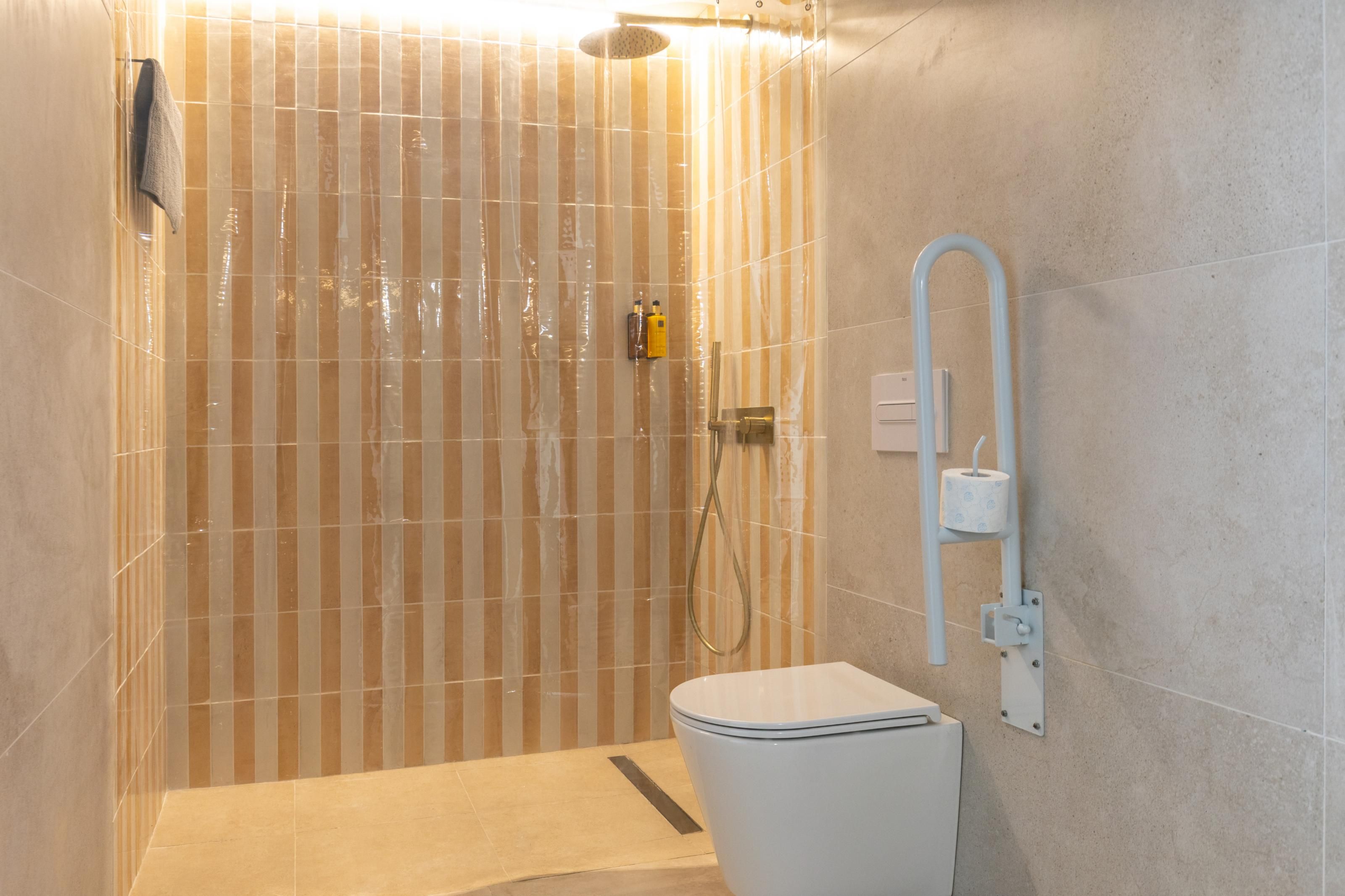 A modern bathroom with a shower, toilet, and a towel rack.