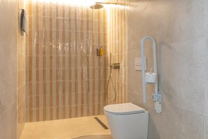 Uma casa de banho moderna com chuveiro, sanita e porta-toalhas.