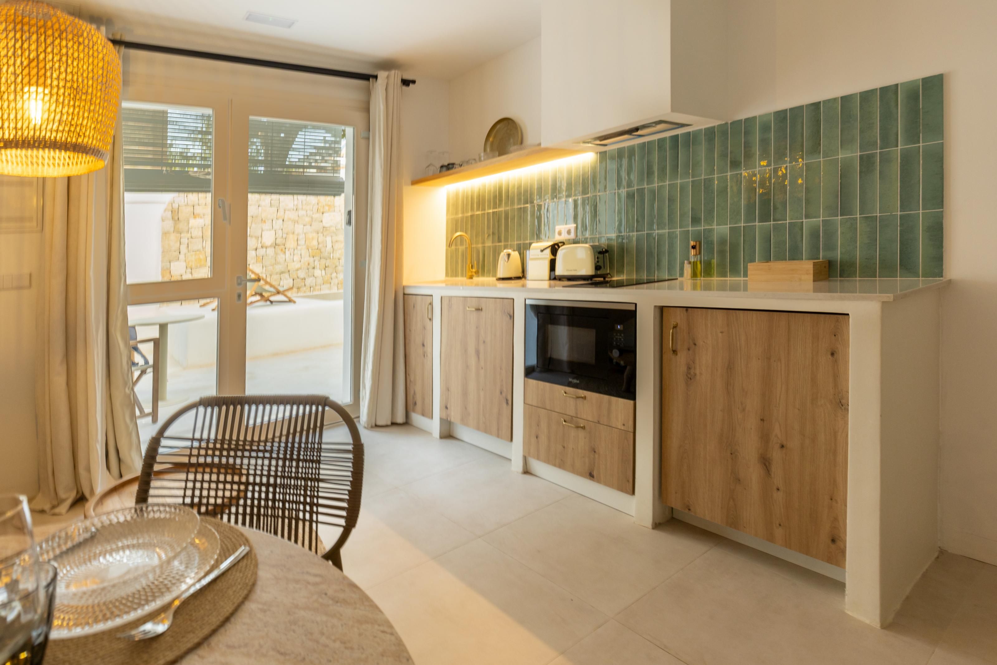 A modern kitchen with wooden cabinets, a built-in oven, and a green tiled backsplash.
