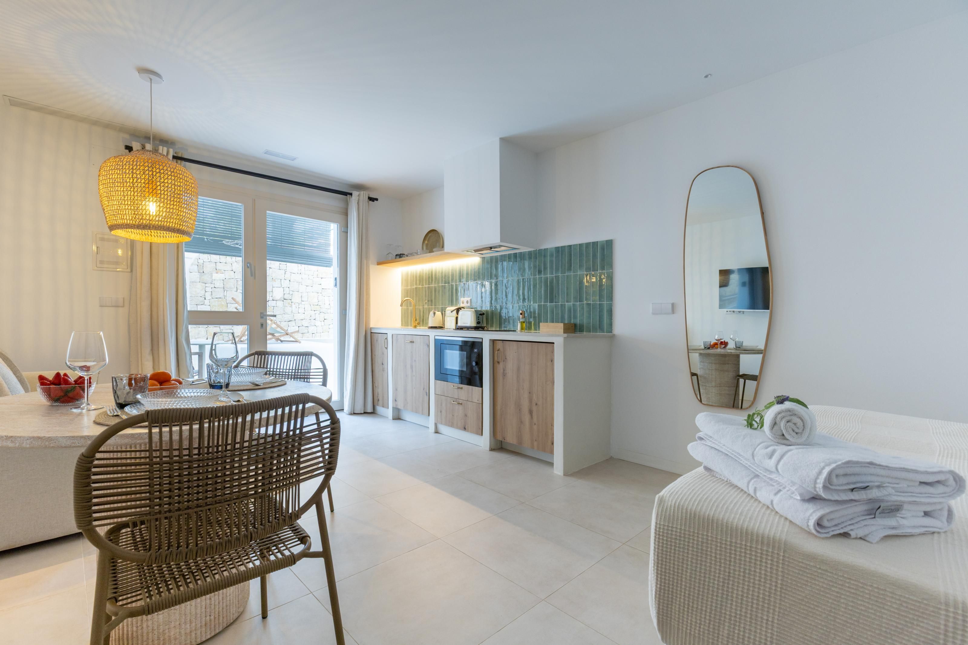 Een moderne keuken met een eethoek, een grote spiegel en een zithoek met een stoel en een tafel.