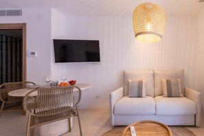 Ein modernes Wohnzimmer mit einem wandmontierten Flachbildfernseher, einer gewobenen Pendelleuchte, einer Couch mit Kissen und einem runden Esstisch mit Stühlen.