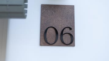 A metallic number plaque with the number 06 affixed to a wall.