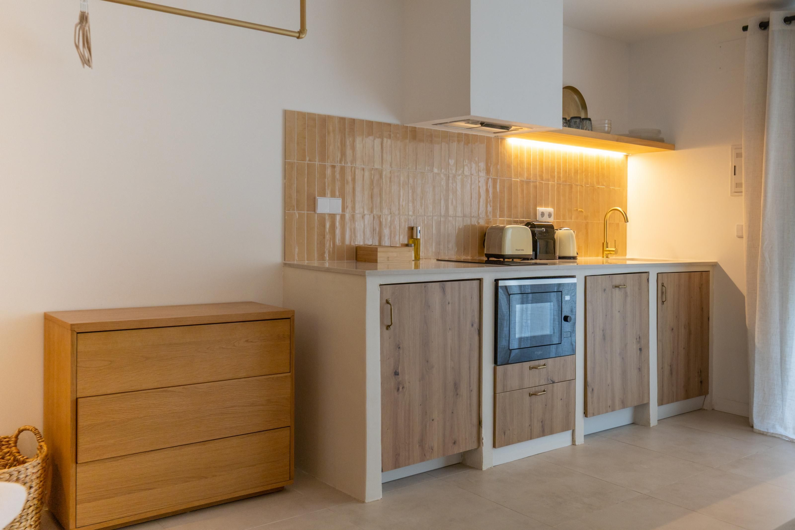 A compact kitchen with a built-in microwave, a toaster, and a sink.