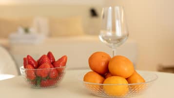 Een eettafel met een glazen schaal vol mandarijnen en een glazen schaal met aardbeien.