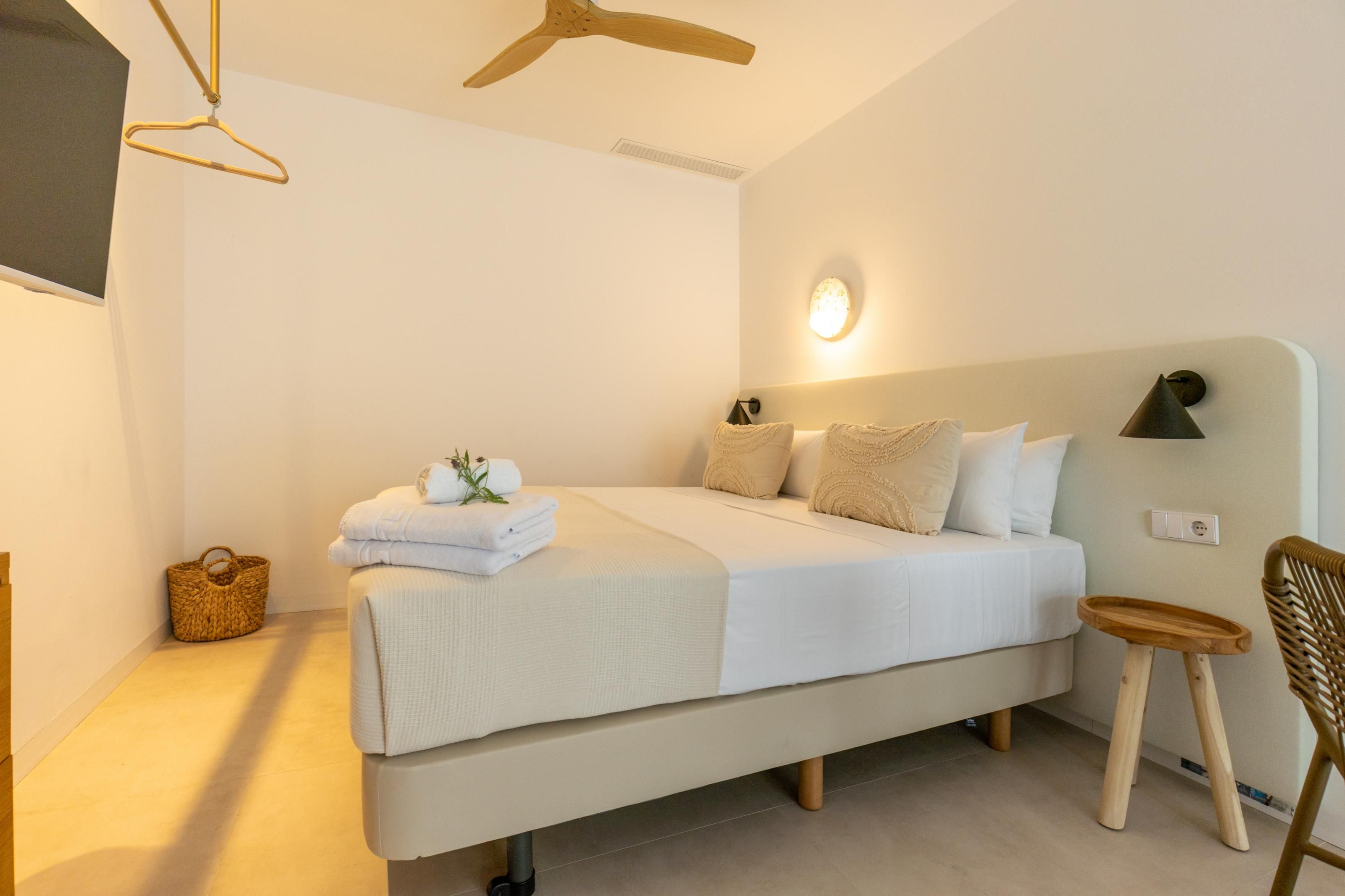 Un dormitorio moderno con cama, mesita de noche, silla y ventilador de techo.