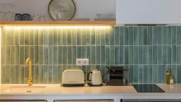 Cocina de diseño moderno, con un lavamanos, un tostador, una cafetera y un hervidor.