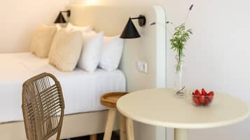 Een slaapkamer met een bed, een stoel, een tafel met een vaas en aardbeien, en een wandlamp.