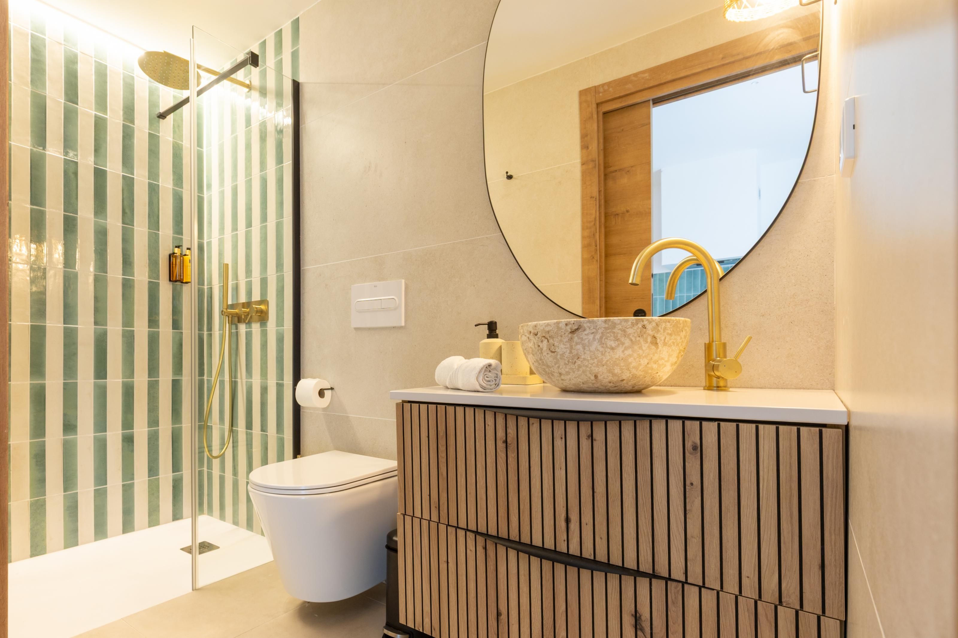 Een moderne badkamer met een douchecabine van glas, een houten wastafelmeubel en een grote spiegel.