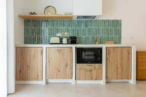 Cozinha com armários de madeira, micro-ondas, torradeira e pia.
