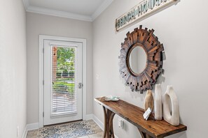 A hallway with a wooden console table, a decorative mirror, and a door with blinds. - 🌊Walk to Beach-Great Location-5BR Driftwood Townhomes🌊 (Miramar Beach)