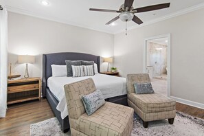 A bedroom with a large bed, two armchairs, a nightstand, a ceiling fan, and a bathroom visible through an open door. - 🌊Walk to Beach-Great Location-5BR Driftwood Townhomes🌊 (Miramar Beach)