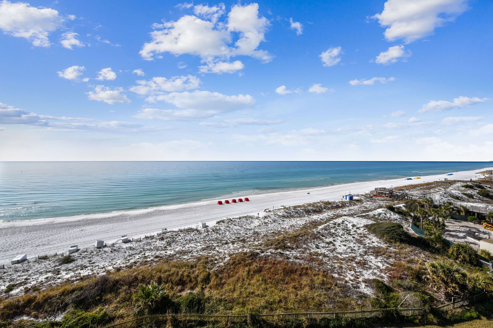 A beach with a clear sky, sandy shore, and sparse vegetation.