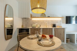 Uma cozinha moderna com mesa de jantar redonda, luminária pendente e televisão de tela plana na parede.
