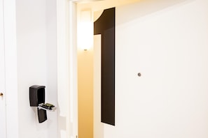 Une porte blanche avec un panneau noir et un petit appareil électronique fixé au mur à côté.