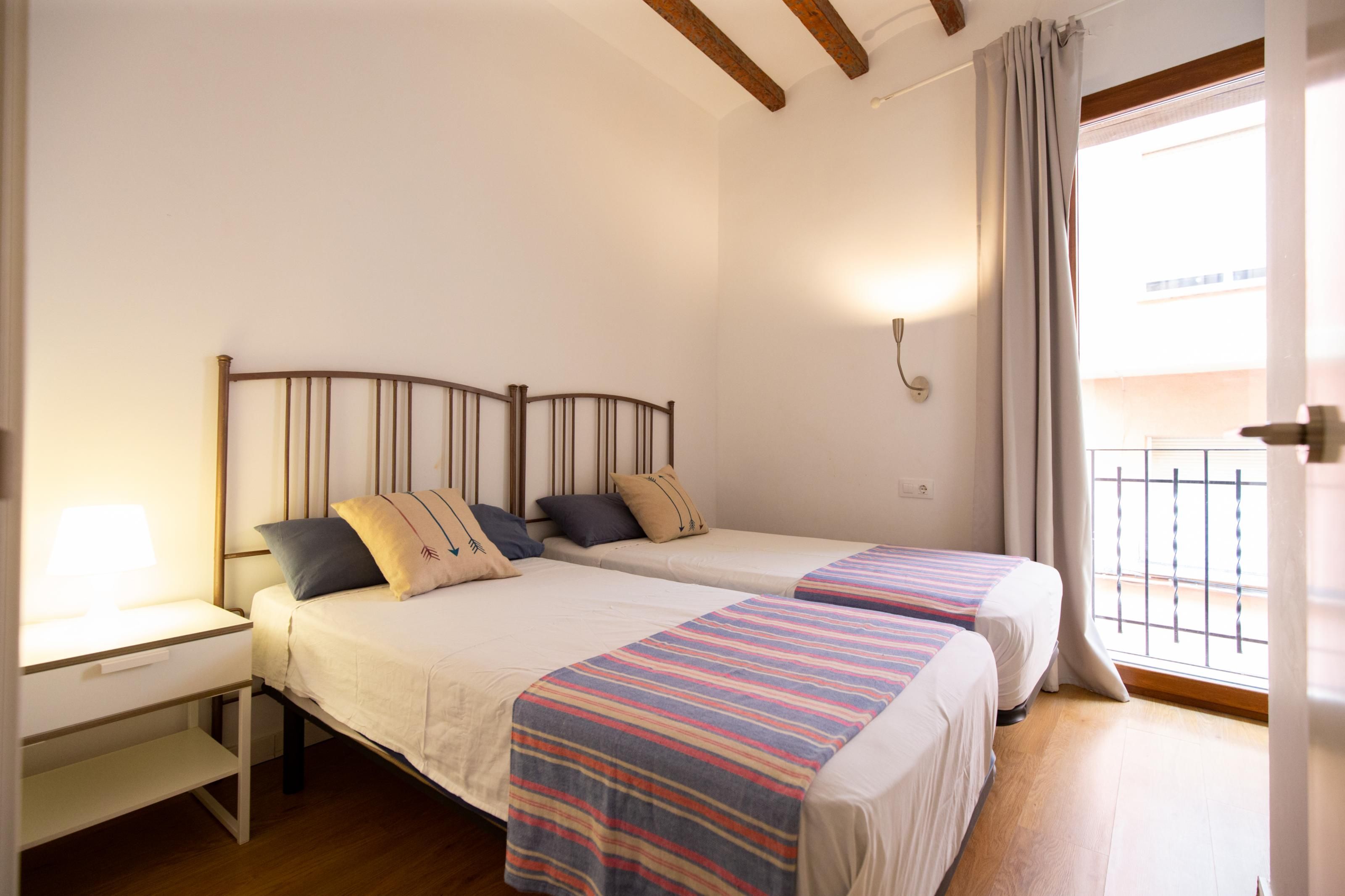 A double bed with a headboard, bedside tables, and a window with curtains.