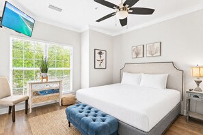 A bedroom with a bed, a ceiling fan, a TV, a window with blinds, and a bedside table. - 🌊Walk to Beach-Great Location-4BR Pet Friendly Beachwaves Driftwood🌊 (Miramar Beach)
