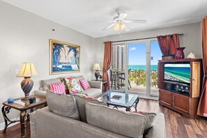 A living room with a sofa, a glass coffee table, a television, and a view of the ocean through a sliding glass door. - ⭐Gulf Views -2 Pools + Kids Fountain-3BR Ariel Dunes I 610-Emerald Eden⭐ (Miramar Beach)