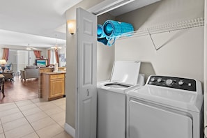 A laundry area with a washing machine, dryer, and a hanging rack with folded items. - ⭐Gulf Views -2 Pools + Kids Fountain-3BR Ariel Dunes I 610-Emerald Eden⭐ (Miramar Beach)