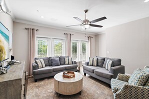 A living room with two grey sofas, a round coffee table, and a ceiling fan. - ⛱️Heated Community Pool-Gorgeous 4BR Townhome-Walk to beach-Emerald Escape⛱️ (Miramar Beach)