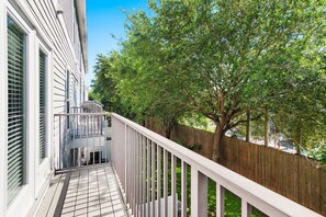 A wooden deck with a white railing, a view of a tree-lined backyard, and a building with large windows. - ⛱️Heated Community Pool-Gorgeous 4BR Townhome-Walk to beach-Emerald Escape⛱️ (Miramar Beach)