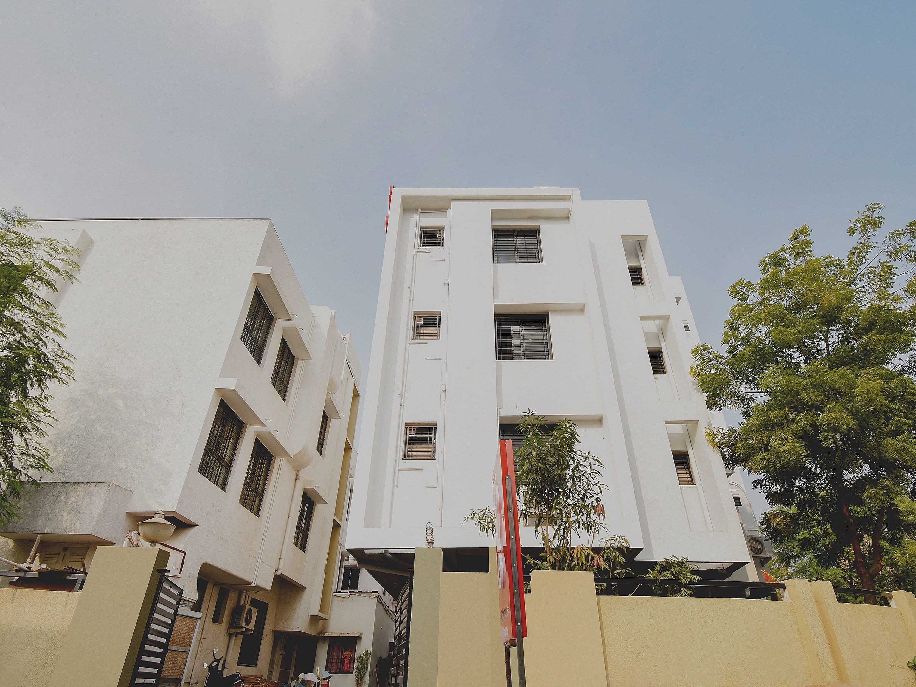 A multi-story building with a flat facade, rectangular windows, and a visible entrance gate.