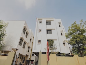A multi-story building with a flat facade, rectangular windows, and a visible entrance gate. - Collection O White House Regency (Nagpur)