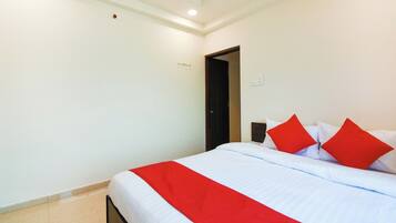 Una habitación de hotel con cama, puerta y un interruptor de luz en la pared.