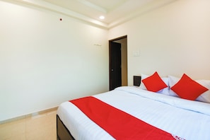 Una habitación de hotel con cama, puerta y un interruptor de luz en la pared.