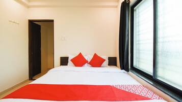 A hotel room with a bed, a window with a view, and a door.