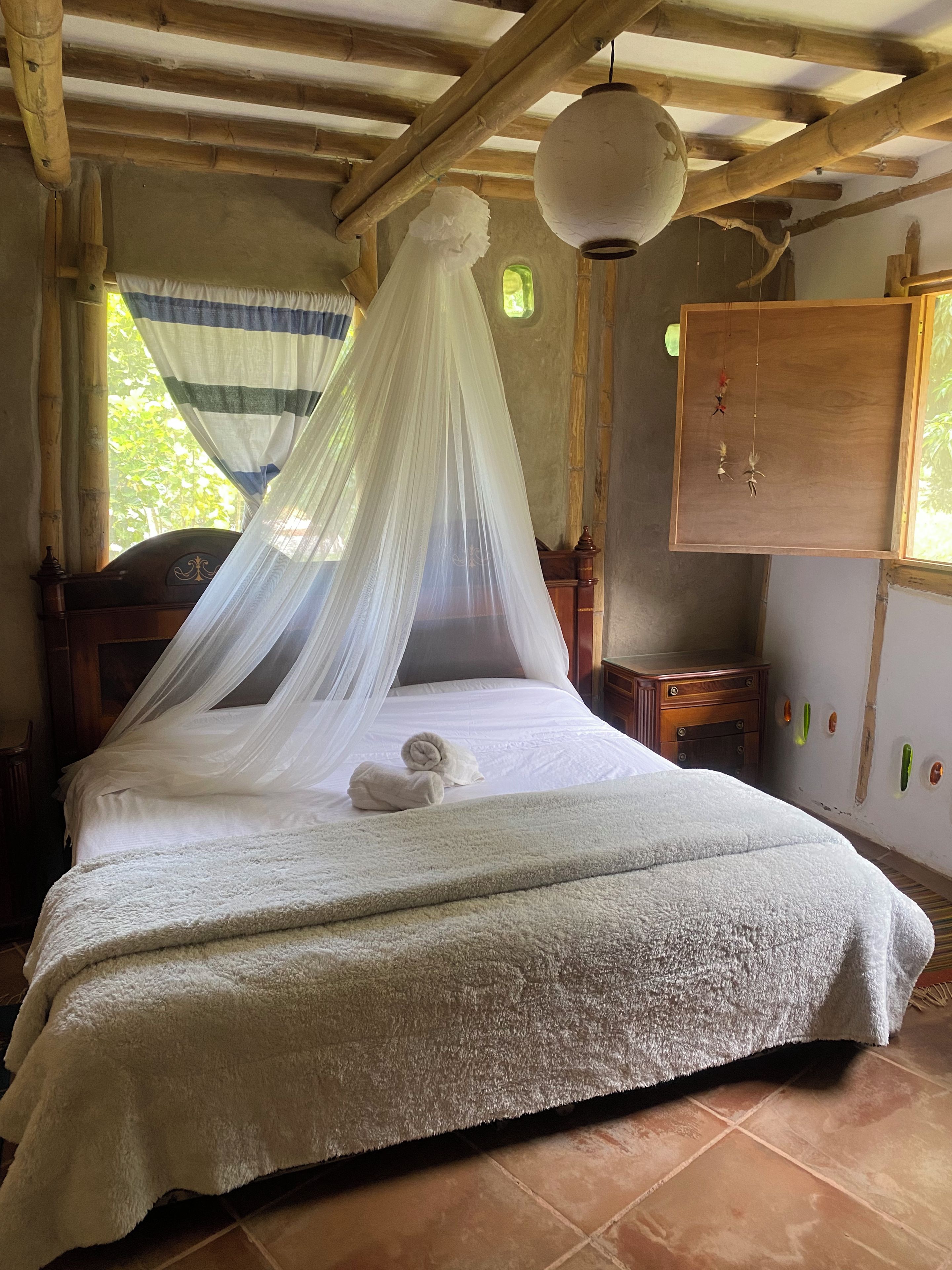 A bed with a canopy, a wooden headboard, a bedside table, and a wall-mounted decoration.