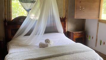 A bed with a canopy, a wooden headboard, a bedside table, and a wall-mounted decoration.