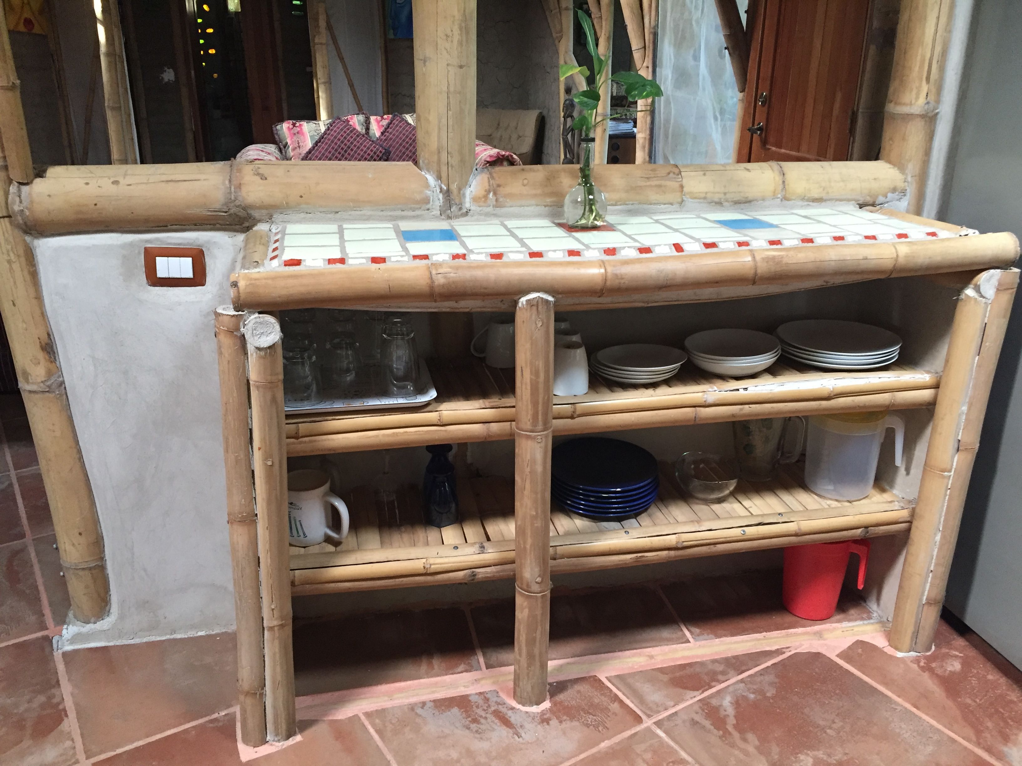 A bamboo shelf unit with storage shelves, a white refrigerator, and a tiled floor.