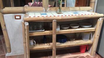 A bamboo shelf unit with storage shelves, a white refrigerator, and a tiled floor.