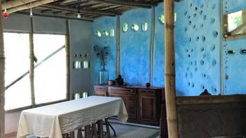 A dining area with a table set for four, a wooden ceiling, and a wall with decorative holes.
