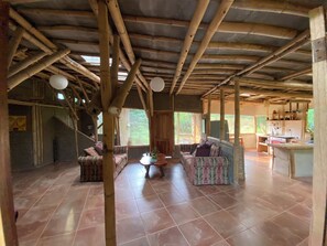 A rustic interior with a bamboo ceiling, a sofa, a small table, and a kitchen area.