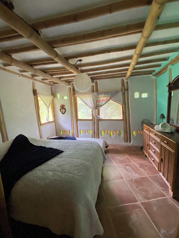 A room with a bed, a wooden dresser, and a window with a view.