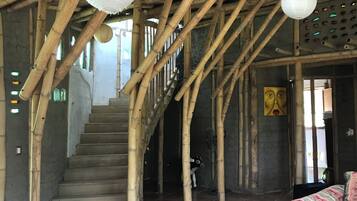 A staircase with bamboo beams, a fan, and a patterned sofa in a rustic interior.
