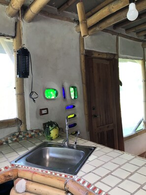 A kitchen with a sink, a wooden door, and a window.