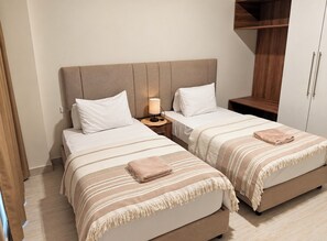 A hotel room with two beds, a bedside table with a lamp, and a wardrobe. - Bohohomes sea view (Red Sea Governorate)