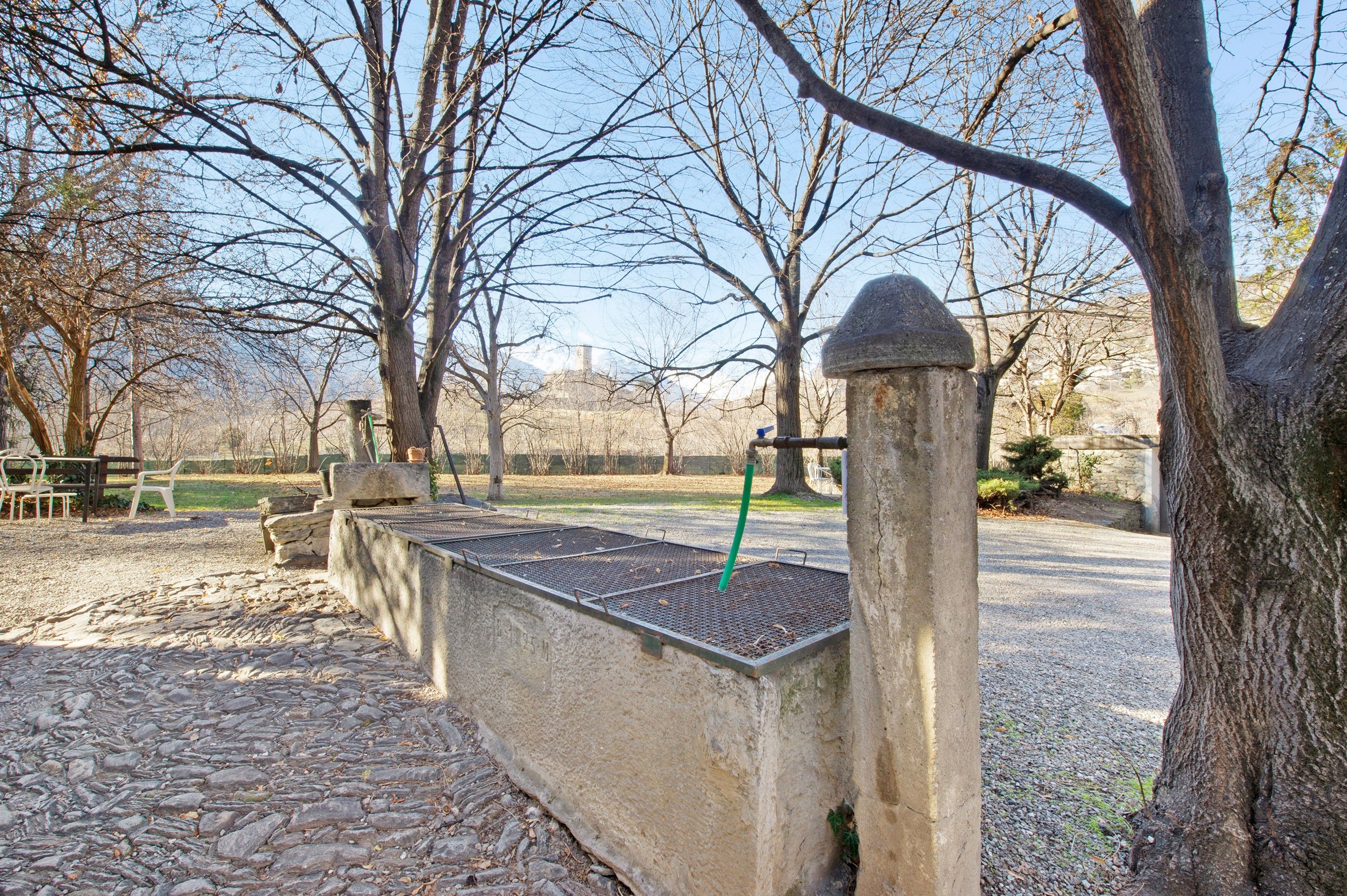Un parc avec un sentier en pierre, des bancs et une clôture en métal.