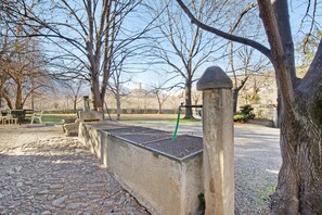 Un parque con un sendero de piedra, bancos y una valla de metal.