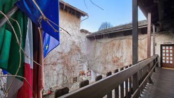 Un bâtiment rustique doté d’un balcon en bois, d’une porte avec des panneaux de verre et de drapeaux.