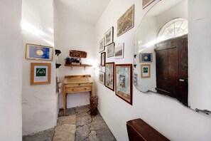 Un estrecho pasillo con un banco de madera, suelo de piedra y varias fotografías enmarcadas en las paredes.