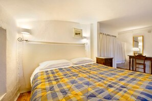 Un dormitorio con cama, mesita de noche, silla, escritorio y espejo.